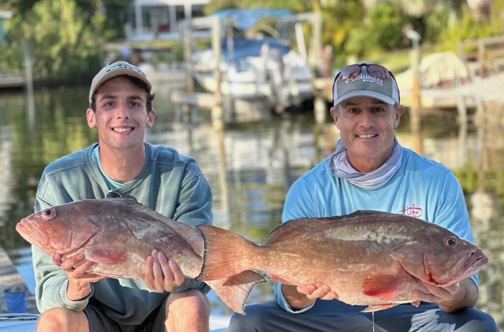 Two people holding fish outdoors