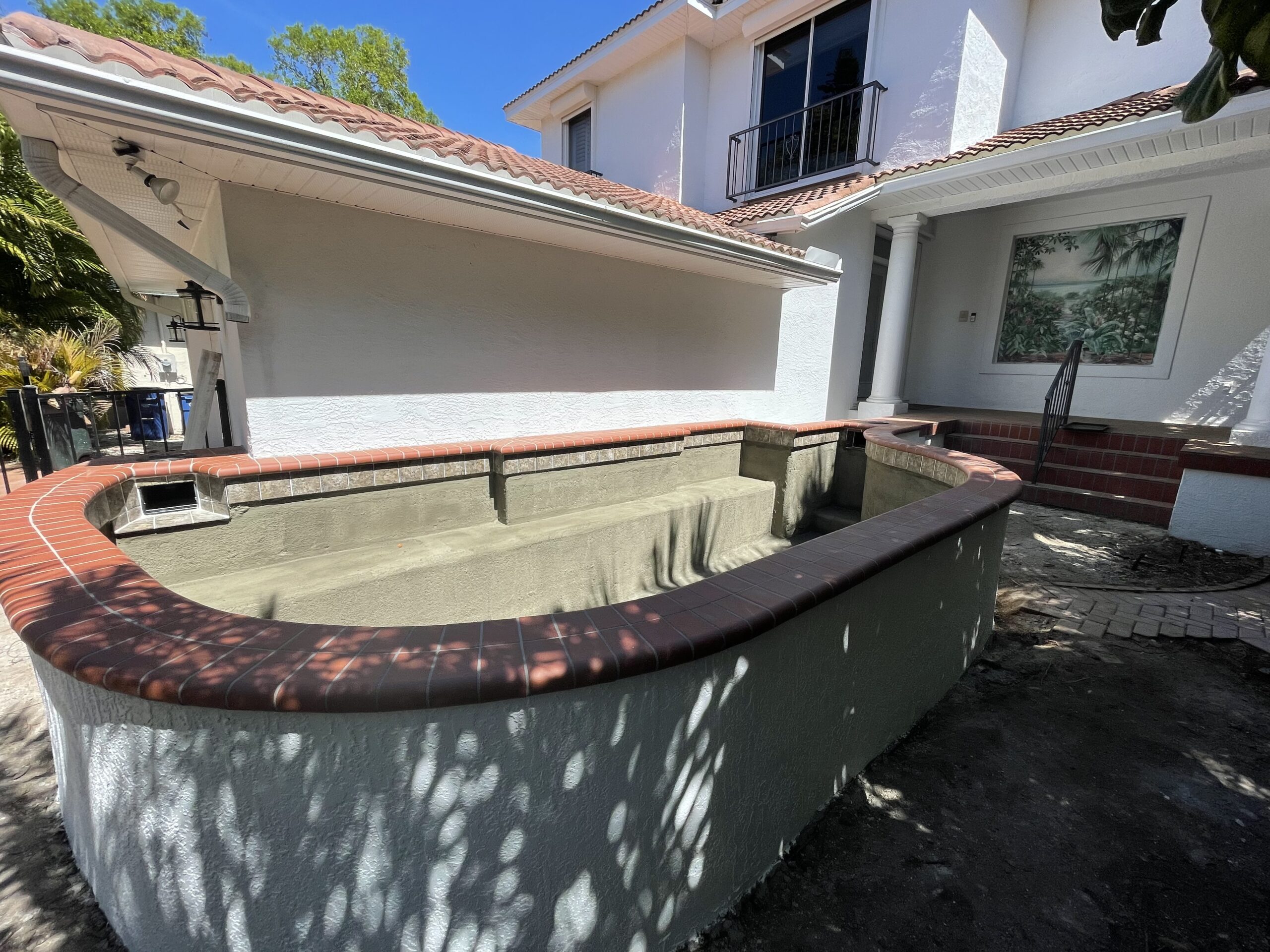 Benjamin Hayt’s empty koi pond during construction, with curved walls and red brick coping.